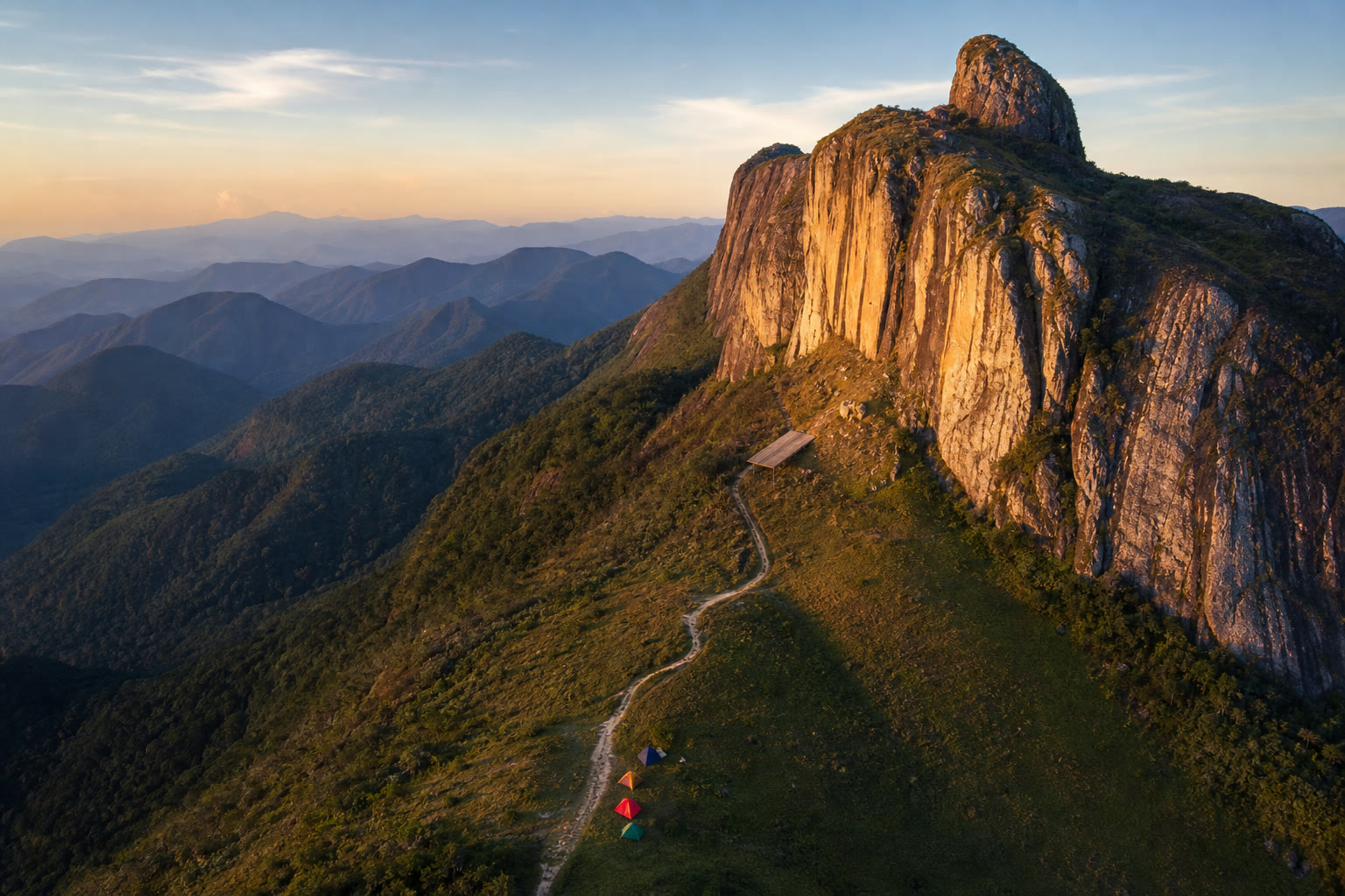 Vista aérea da serra com o paredão de pedra e o parapente em voo